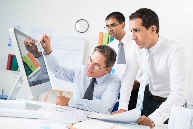 Group of business people pointing intensely at a monitor